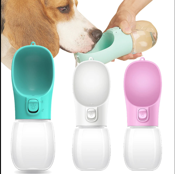 Portable dog water bottle in teal, white and pink with dog drinking from it